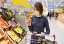 Young woman wearing disposable medical mask shopping in supermarket during coronavirus pneumonia outbreak.