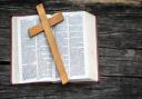 A wooden cross sits on top of an open  bible