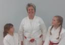 Ruth proudly wearing her Red and White belt award, along with two of her young students