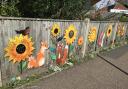 Colourful decorations on the fence, and flowers finally blooming along the base