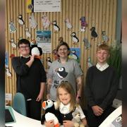 Academy students display some of their puffin artwork, with receptionist Kelly